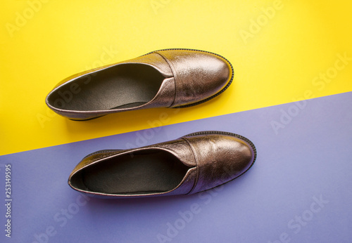 Pair of sparkly female shoes on yellow and purple background with copyspace. Flat lay style.