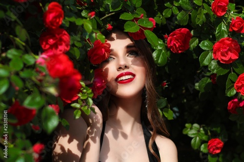 Portrait of  beautiful young woman in the rose garden  spring time  rose flowers blossoms.