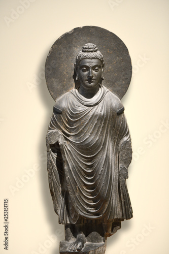 Standing Buddha Shakyamuni stone sculpture in grey schist with halo  urna forehead mark  ushnisha head bump and Greco-Roman toga