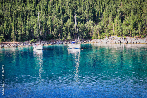 Two sailboats anchored in an emerald bay