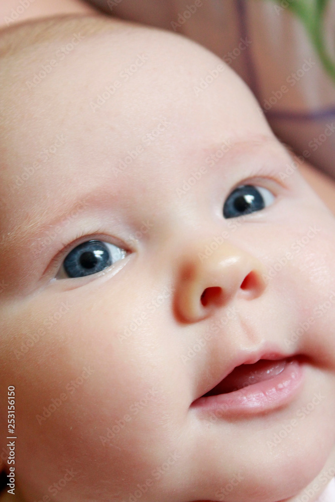 Portrait of smiling baby with blue eyes. Newborn child looking at mother
