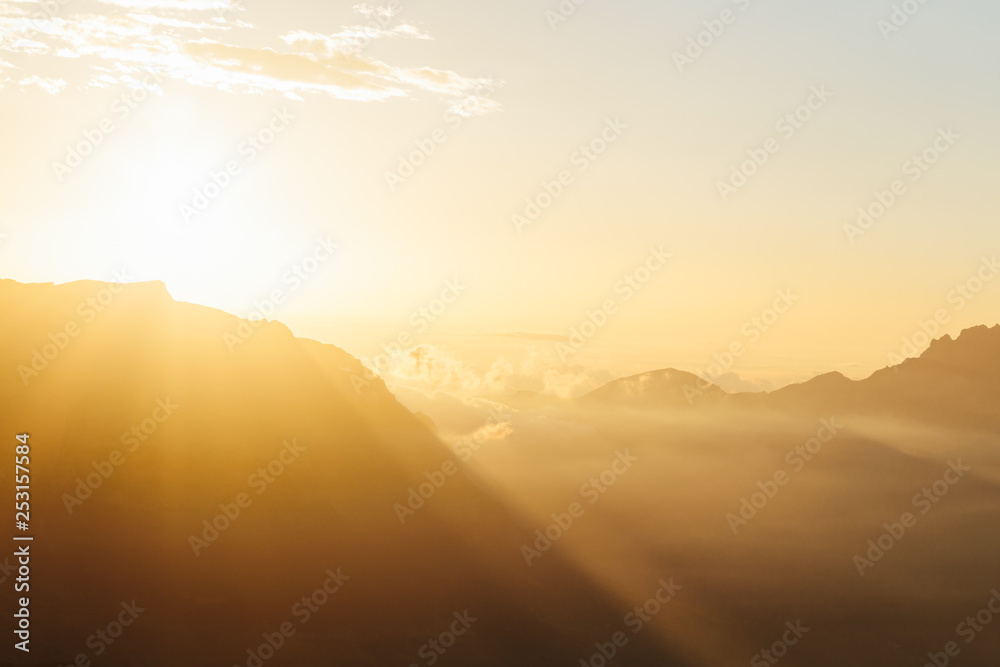 Morning landscape with bright sun rays in haze over mountain silhouettes. Republic of North Ossetia–Alania, Russia