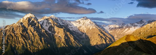 Fantastic morning panorama of beautiful rocky snow-capped mountains of Main Caucasian Ridge at sunrise, dramatic clouds in the sky. View from Republic of North Ossetia - Alania, Russia © Vitaliy Kaplin
