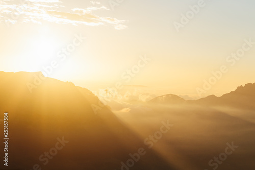 Morning landscape with bright sun rays in haze over mountain silhouettes. Republic of North Ossetia–Alania, Russia