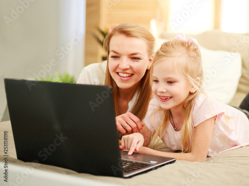 Happy family mother with daughter using computer laptop at home, modern lifestyle