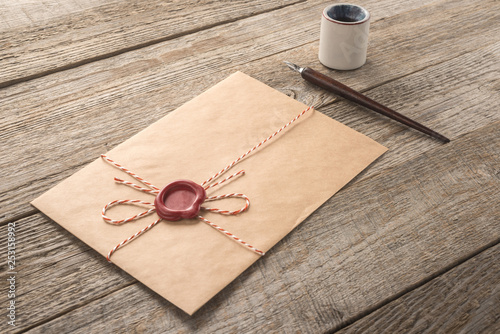   Envelope, ink pen, inkwell on a wood table 