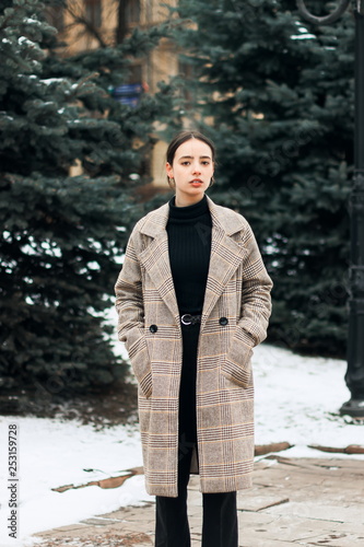 Outdoor portrait of young beautiful brunett girl in grey coat