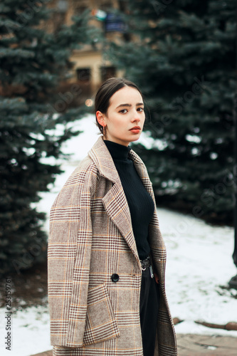 Outdoor portrait of young beautiful brunett girl in grey coat