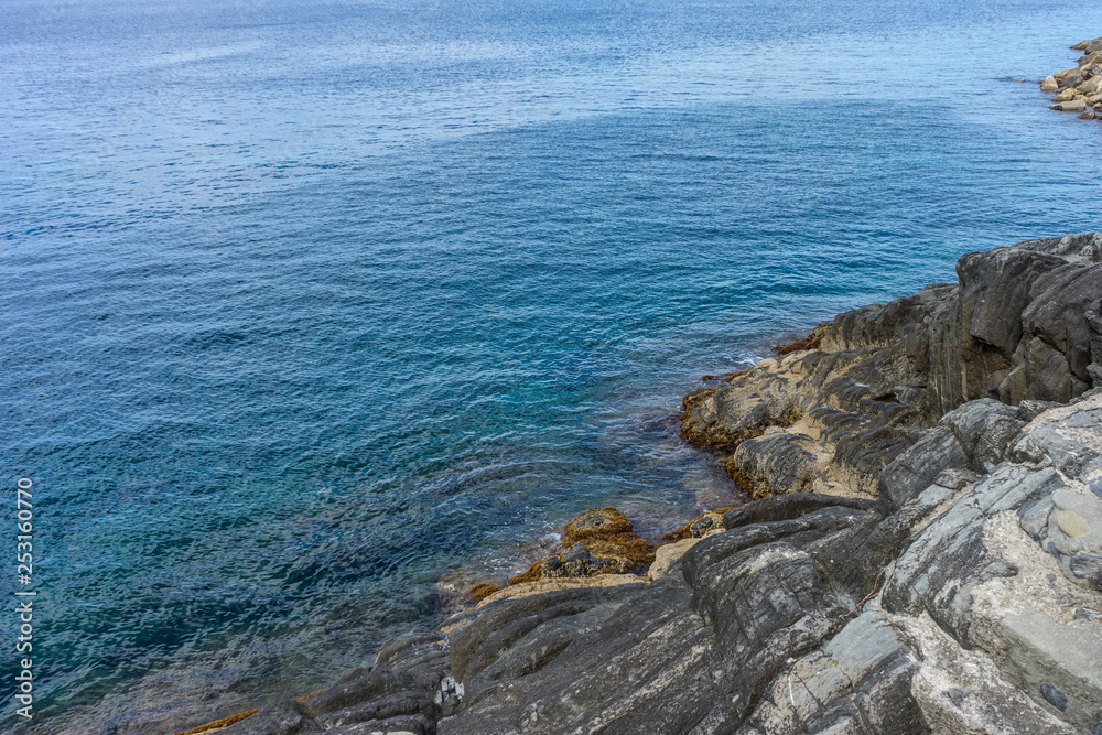 Italy,Cinque Terre,Riomaggiore, a rocky shore next to a body of water