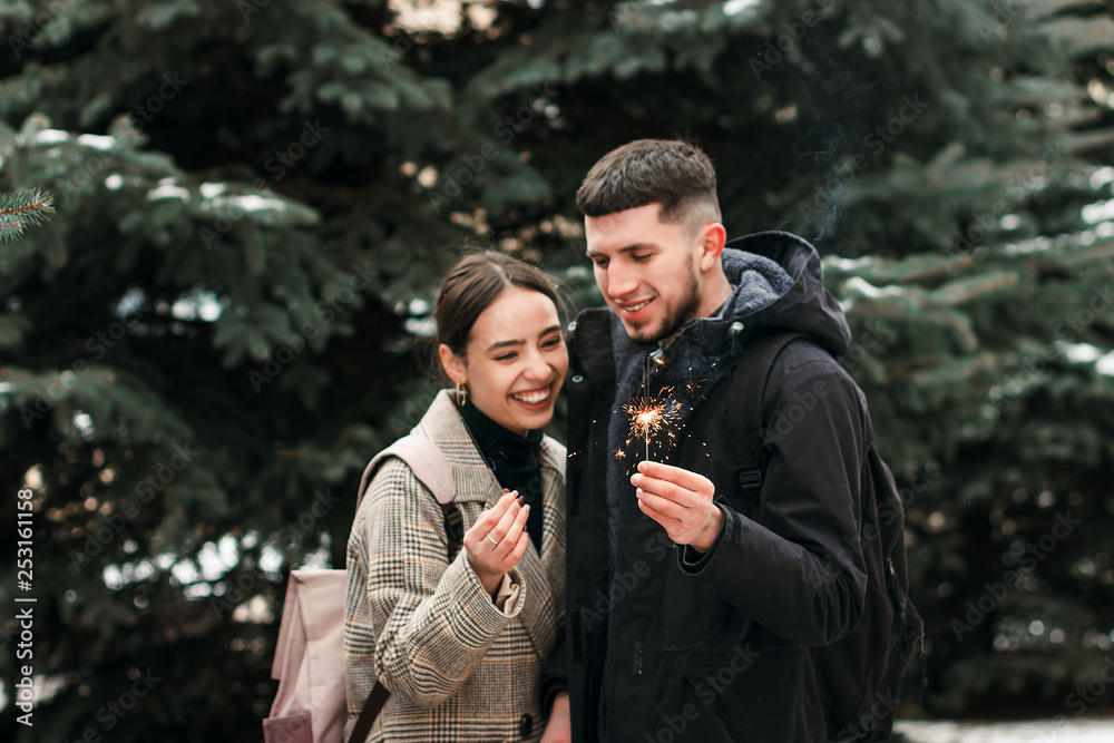 Fototapeta premium A young couple laughing with bengal lights in the hands