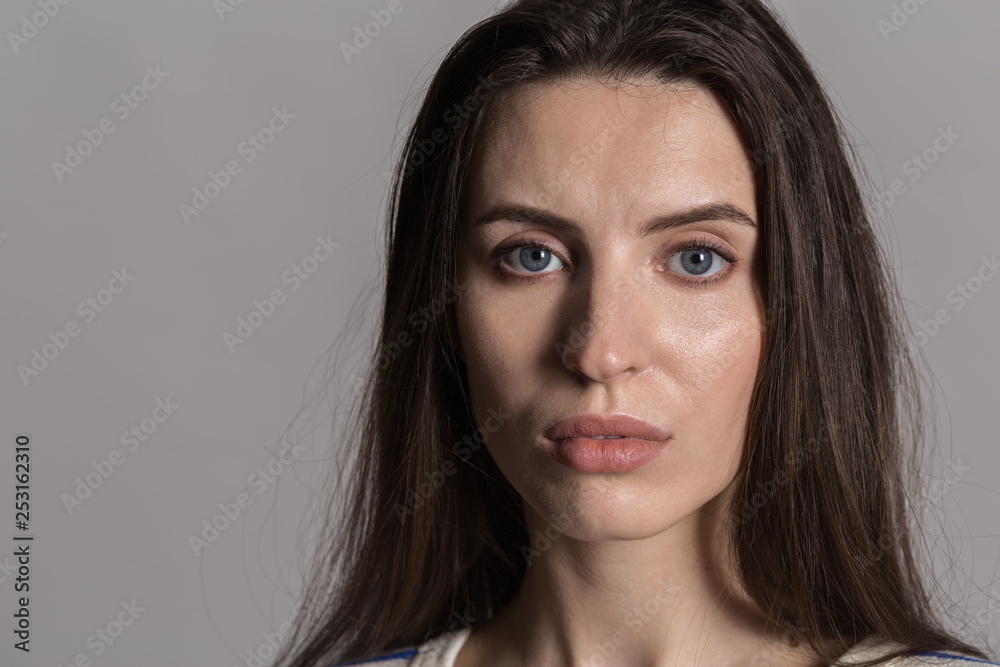 Pretty woman with fluffy hair, dressed casually against a gray studio wall Pretty woman with fluffy hair, dressed casually against a gray studio wall