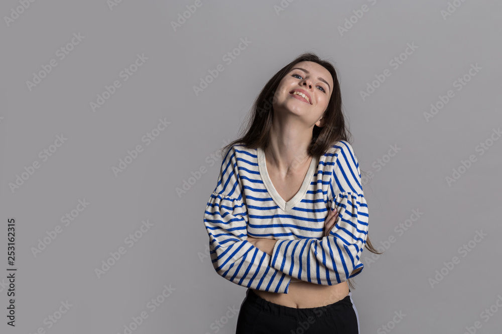 Pretty woman with fluffy hair, dressed casually against a gray studio wall Pretty woman with fluffy hair, dressed casually against a gray studio wall