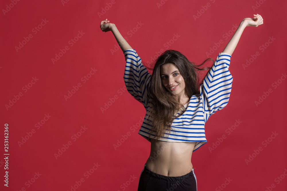 Studio shot of a lovely beautiful woman isolated against an empty red studio wall. Studio shot of a lovely beautiful woman isolated against an empty red studio wall.