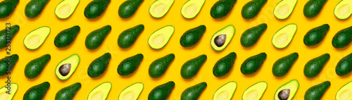 Ripe sliced avocado pattern on yellow background top view. Creative food composition Flat lay. Pop art design, tropical summer abstract background with avocado. Green avocadoes pattern. Banner.