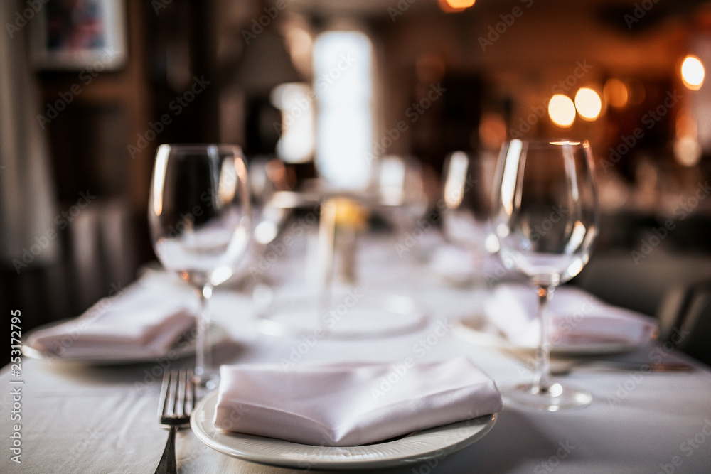 A close up shot of a restaurant table set up with tableware and wine glass. Concept of dining, hospitality and catering. Horizontal image with free space for text.