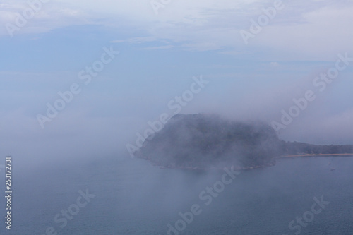 Barrenjoey lighthouse on a hill hidden by thick low clouds over ocean