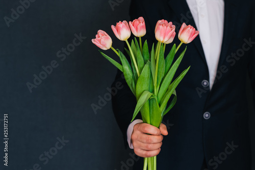 man's hand giving a bouquet of pink tulips