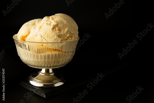 Vanilla Ice Cream scoops in glass elengant cup. Isoalted over black background with copy space. Summer, refreshing ice cream. photo