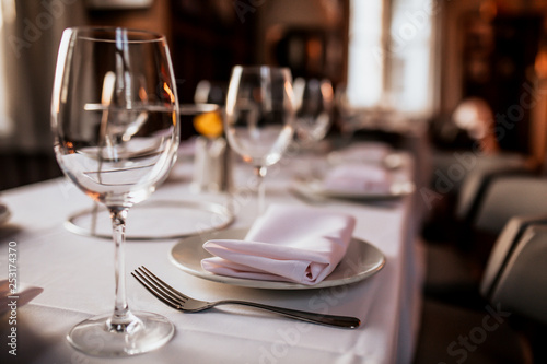 A close up shot of a restaurant table set up with tableware and wine glass. Concept of dining, hospitality and catering. Horizontal image with free space for text. photo