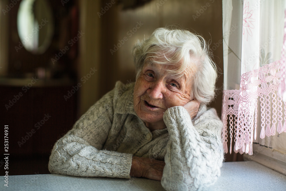 Gray-haired old woman sitting near the window. Gray-haired old woman sitting near the window.