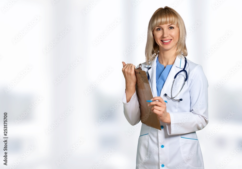 Attractive young female doctor with blurred hospital interior on background Attractive young female doctor with blurred hospital interior on background