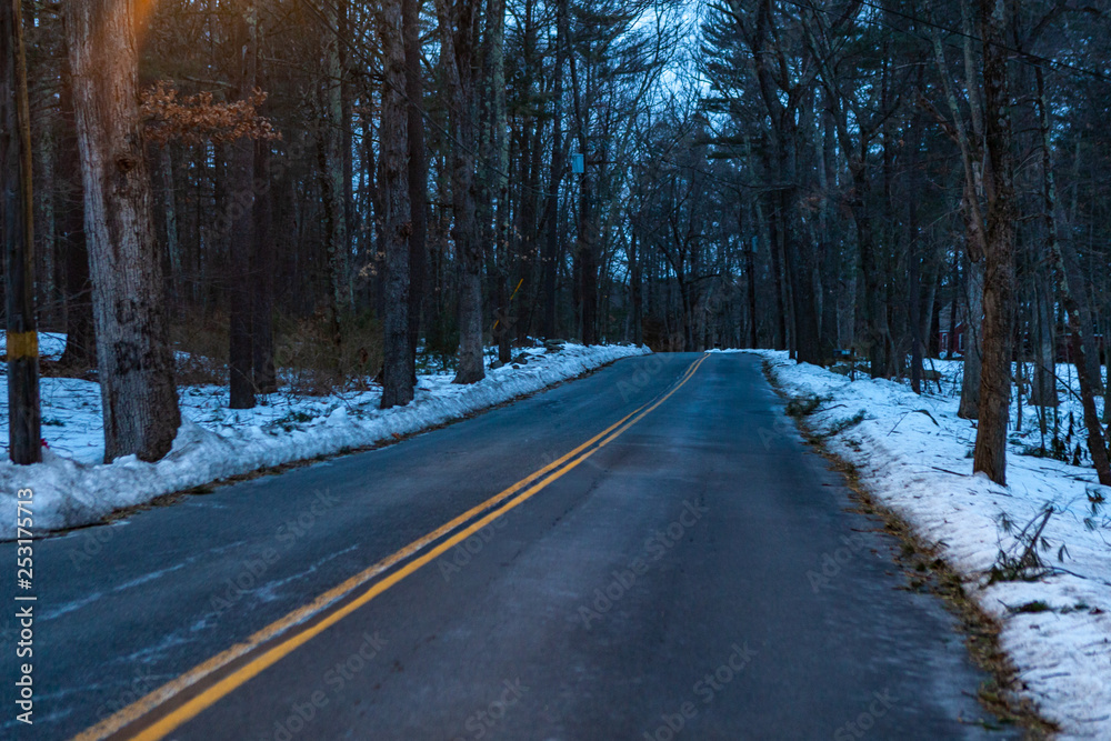Acton, United States, February 27, 2019. Forest road with double yellow line in winter time, Massachusetts, United States Acton, United States, February 27, 2019. Forest road with double yellow line in winter time, Massachusetts, United States