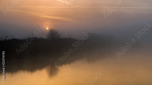 fiume con argine all'alba con nebbia del primo mattino