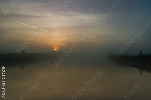 fiume con argine all'alba con nebbia del primo mattino