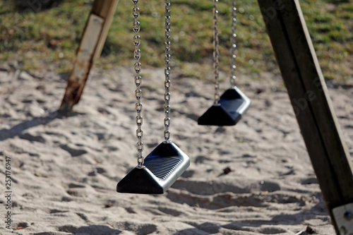 Auf einem Spielplatz steht eine leere Schaukel mit zwei Plätzen