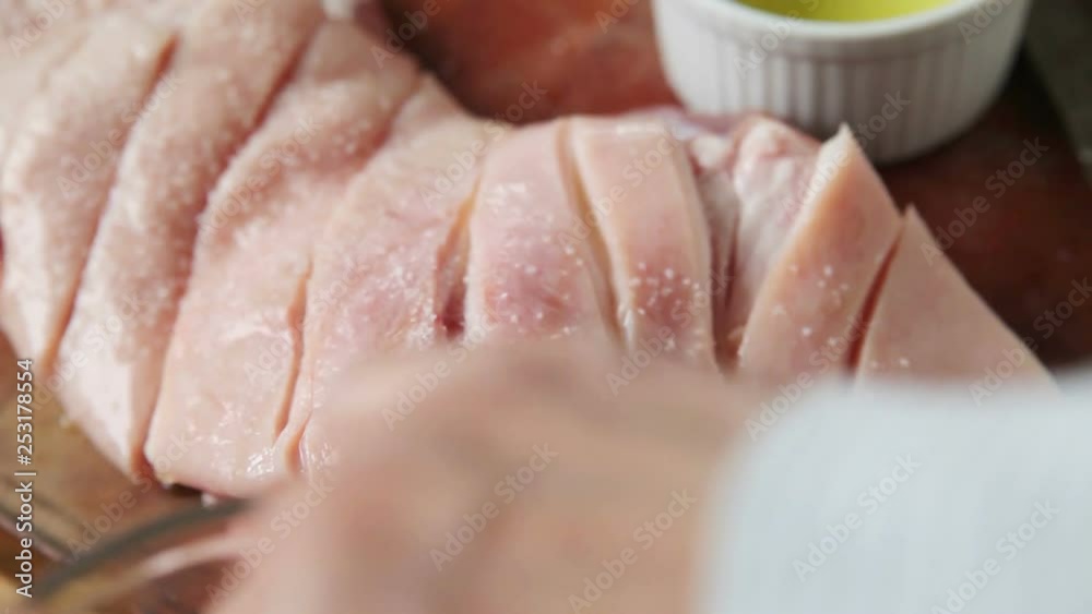 Seasoning a piece of pork with kosher salt and mixed spices