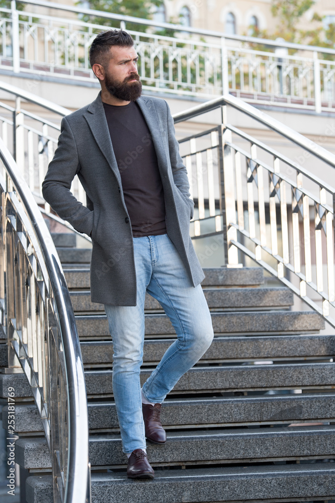 Down the stairs. Stylish casual outfit spring season. Menswear and male fashion concept. Man bearded hipster stylish fashionable coat or jacket. Comfortable outfit. Hipster fashion model outdoors