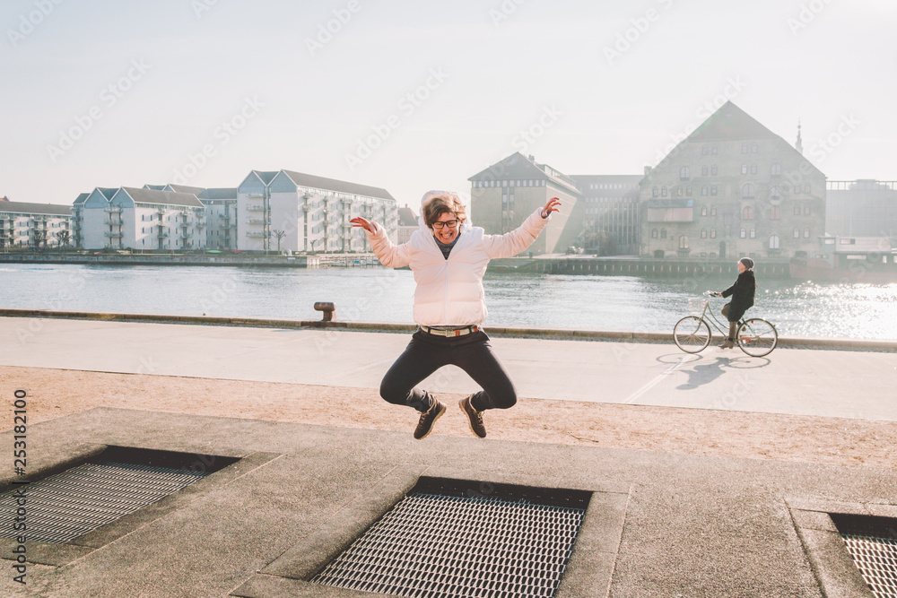 Fest sammensværgelse omfavne adult person rejoices like child. Playground trampoline in ground, children  trampoline, springs throws people up fun and cool. Copenhagen River  Embankment Denmark. Woman jumping on street trampoline Stock Photo | Adobe  Stock