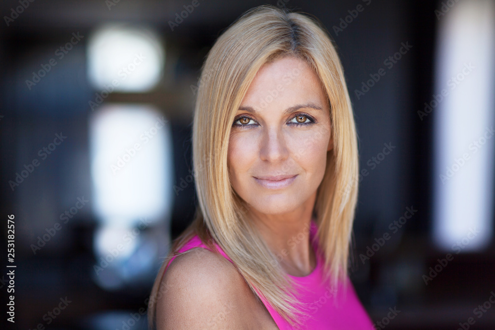 Obraz premium Portrait Of A Mature Woman Smiling At The Camera On a window background