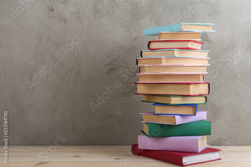 Education and reading concept - group of colorful books on the wooden table, concrete wall blackboard