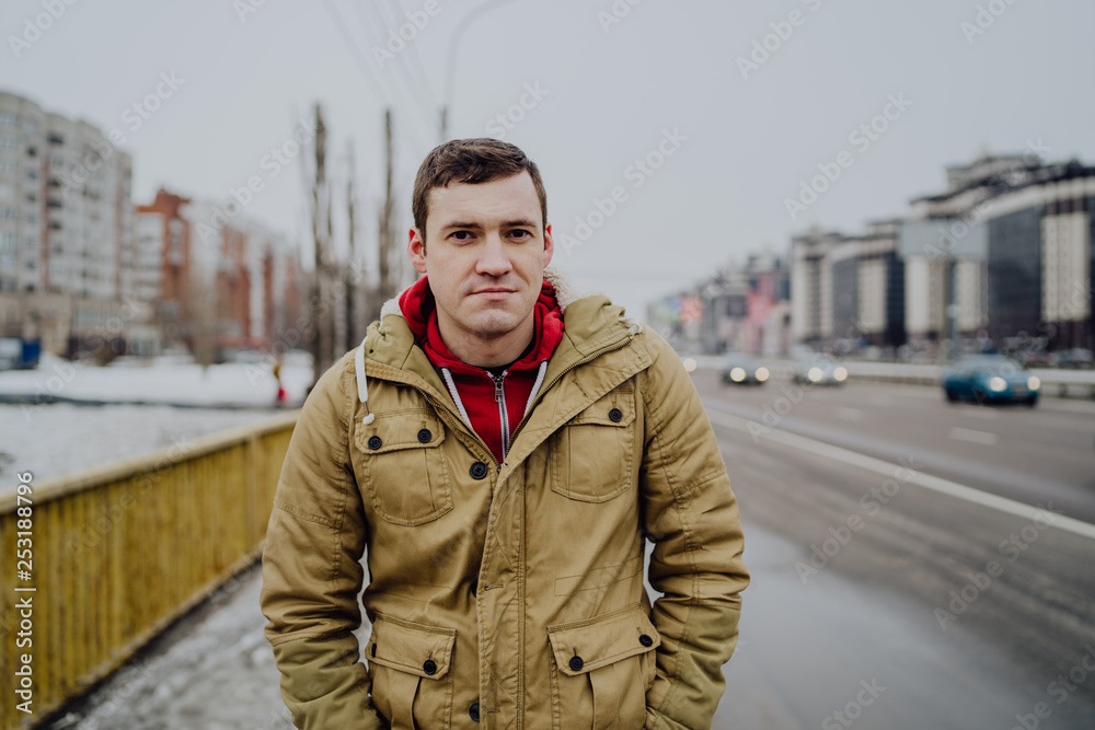 Young man on a bridge in a big city is looking into the distance