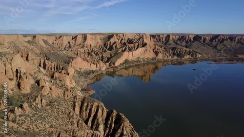 Aerial view on a lake next to a large canyon with reflections in the water