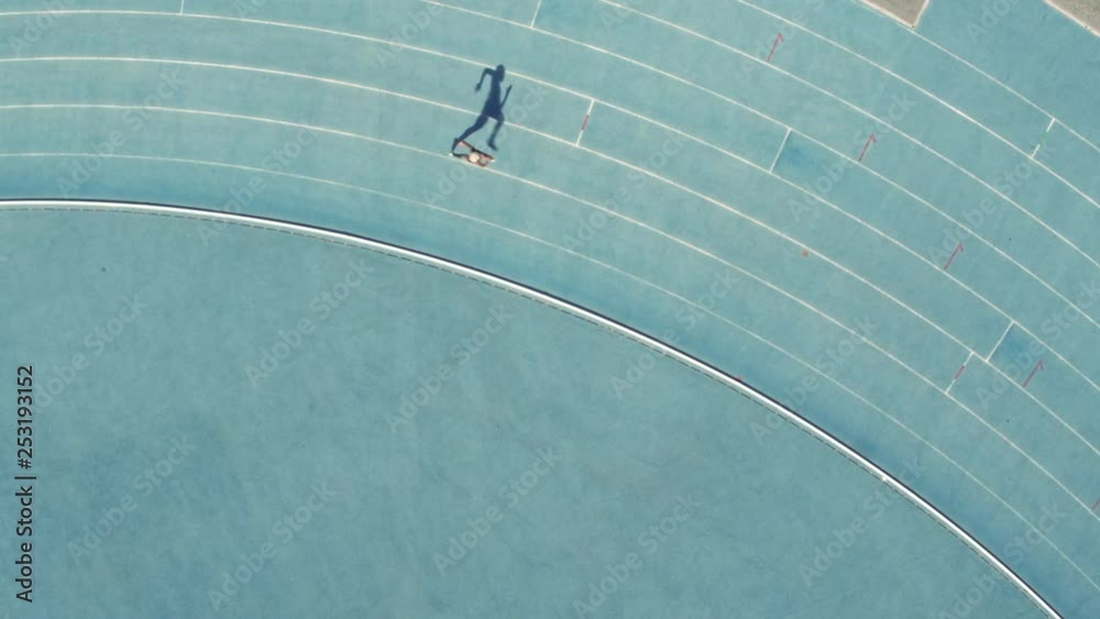 Aerial view of female runner practicing on all weather race track in stadium. Sports woman training athletics running race track.