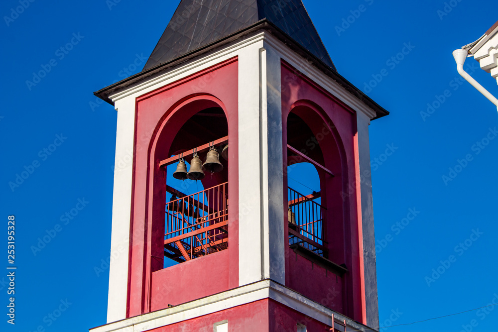 Square bell tower of the Russian Orthodox Church against the blue sky