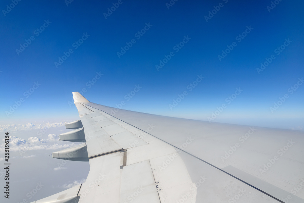 Fototapeta premium Beautiful clear deep blue sky over thick layer of clouds at stratosphere atmosphere viewed from airplane's window located above airplane's wing and jet.