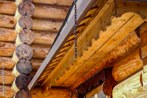 Wooden architecture and water dripping from the roof, thaw