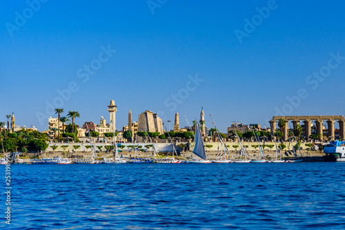 Different vessels near the bank of the Nile river in Luxor, Egypt. Luxor temple on background