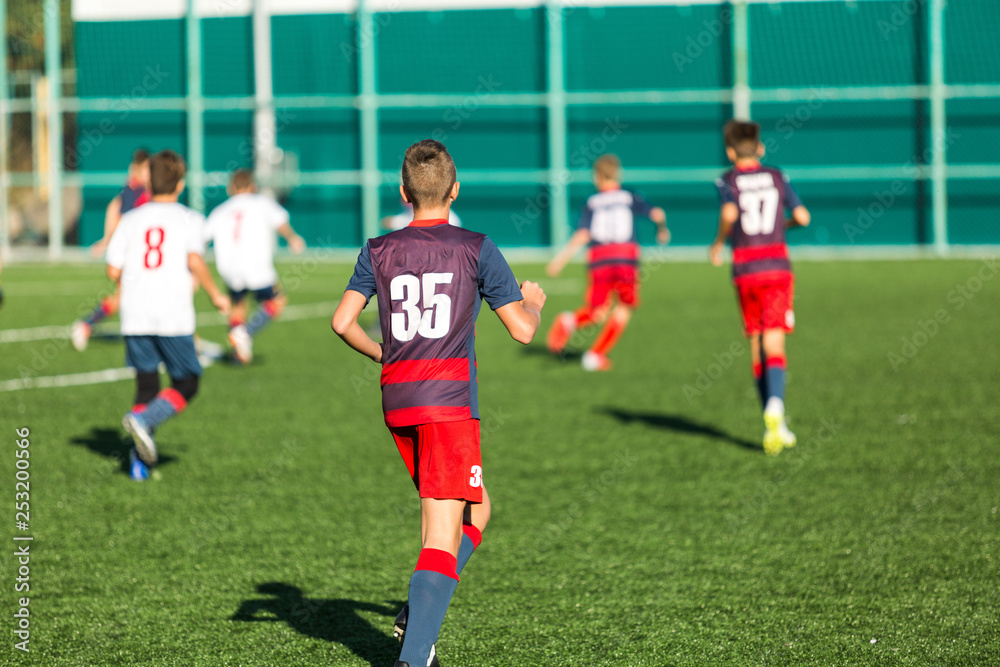 Fototapeta premium Football training soccer for kids. Boy runs kicks dribbles soccer balls. Young footballers dribble and kick football ball in game. Training, active lifestyle, sport, children activity concept