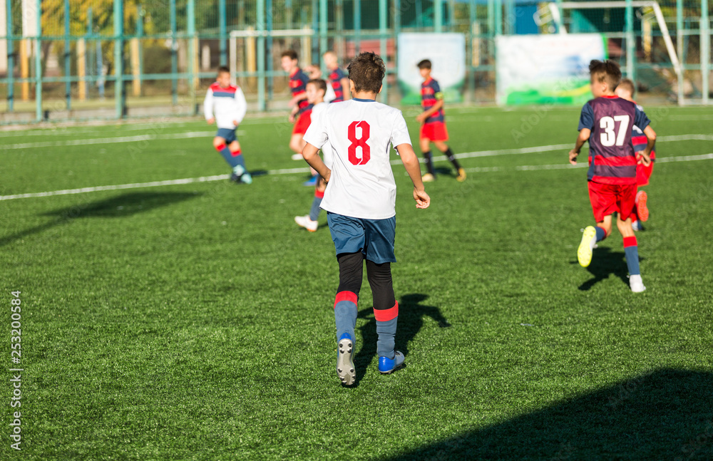 Obraz premium Football training soccer for kids. Boy runs kicks dribbles soccer balls. Young footballers dribble and kick football ball in game. Training, active lifestyle, sport, children activity concept 