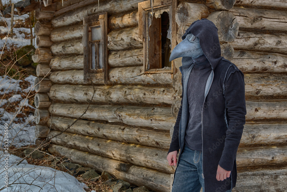 A tall man in a mask of a plague doctor (or a crow) and a black hooded ...