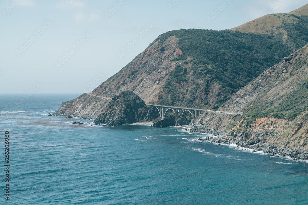 Scenic panoramic view of historic Bixby Creek Bridge along world famous Highway 1 in beautiful sunny day with dramatic cloudscape. big sur in Monterey County California USA. blue pacific ocean sky