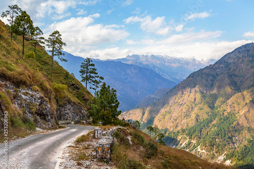 Scenic mountain road with distant Himalaya snow peaks and mountain valley near Kausani Uttarakhand India