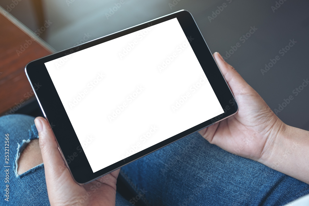Mockup image of a woman sitting and holding black tablet pc with blank white desktop screen horizontally Mockup image of a woman sitting and holding black tablet pc with blank white desktop screen horizontally