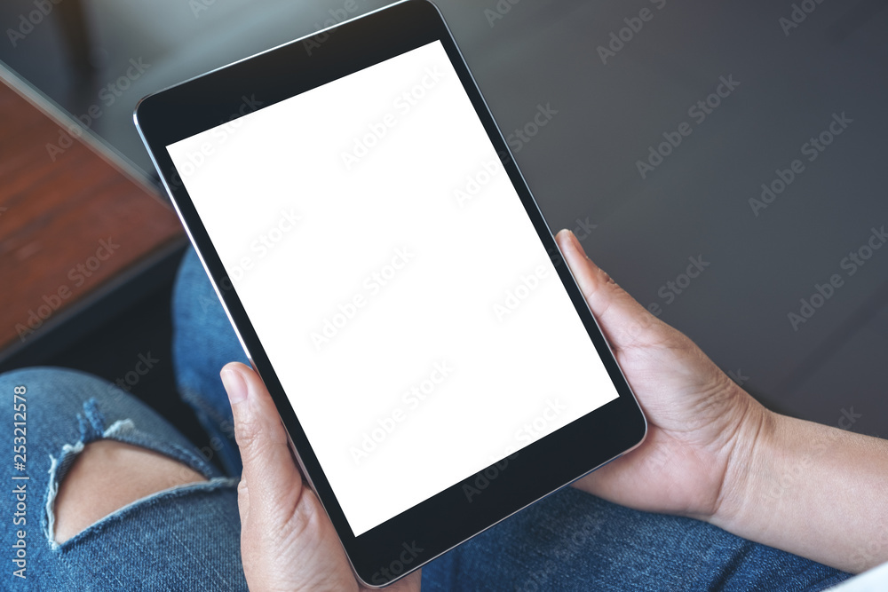 Mockup image of a woman sitting and holding black tablet pc with blank white desktop screen Mockup image of a woman sitting and holding black tablet pc with blank white desktop screen