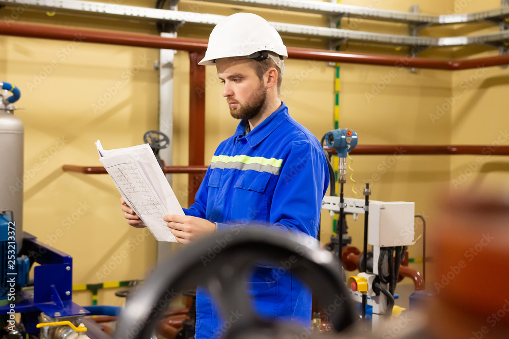 Engineer working with technical documentation during maintenance industrial equipment in refinery plant.