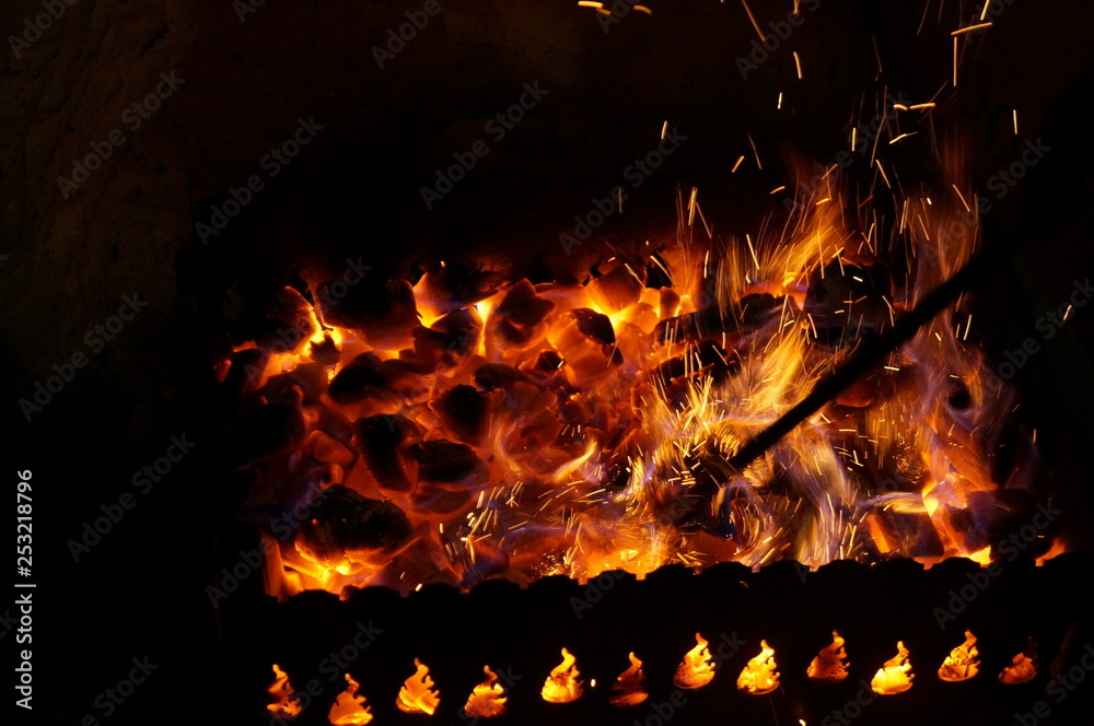 Obraz premium hot wood coals burn with bright flame in iron brazier.